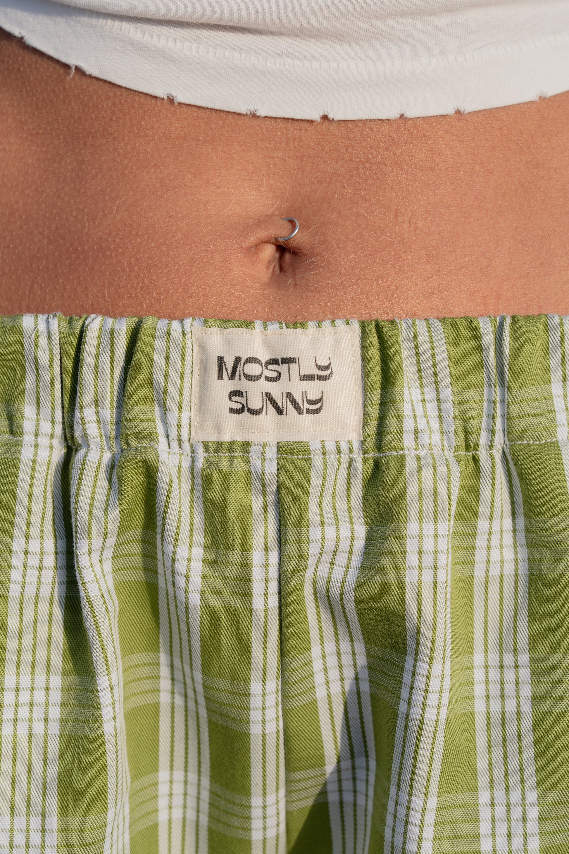 Palaka avo lounge pants with 'Mostly Sunny' label on a person wearing them.